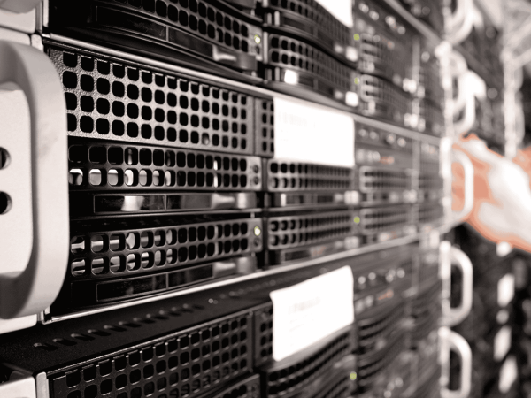 Close-up of a person working on a server rack in a data center, showing multiple black server units with indicator lights and network cables.