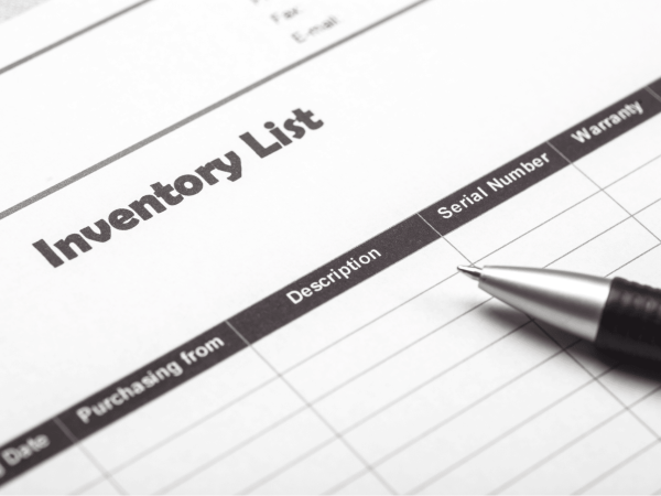 Close-up of an IT device inventory list form with columns for description, serial number, and warranty, alongside a pen, representing IT asset tracking and management services provided by an MSP in the San Francisco Bay Area.