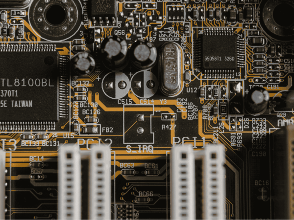 Close-up of a computer motherboard with integrated circuits, capacitors, and PCI slots, representing IT hardware and tech support services for businesses in the San Francisco Bay Area.