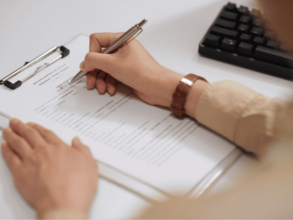 Close-up of a person completing paperwork during the employee off-boarding process – documenting account deactivation and data security procedures.