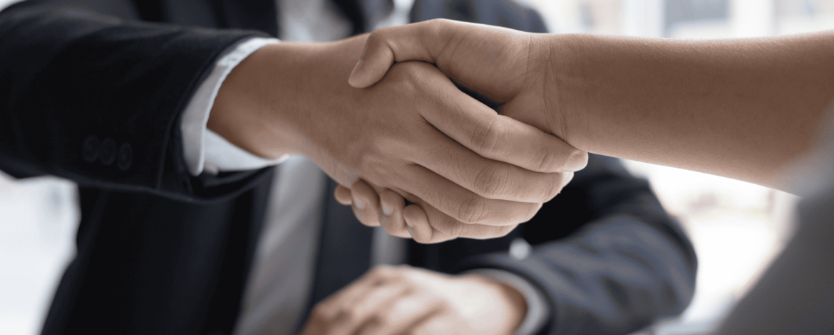 Business professional shaking hands with a new hire during onboarding – secure account setup and IT provisioning as part of an organized onboarding process.