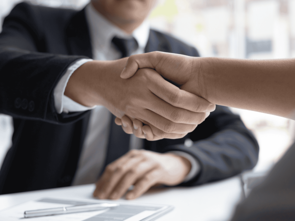 Business professional shaking hands with a new hire during onboarding – secure account setup and IT provisioning as part of an organized onboarding process.