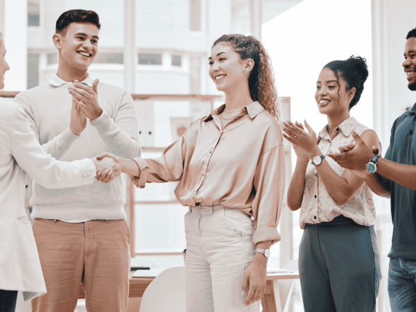 Team welcoming a new employee with handshakes and applause – smooth IT onboarding ensuring proper access, permissions, and device setup.