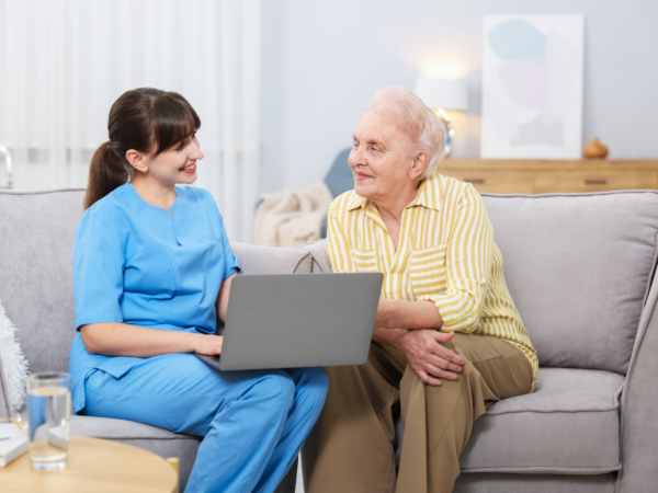 Home care nurse assisting elderly patient with mobility walker in senior living environment supported by secure healthcare IT systems