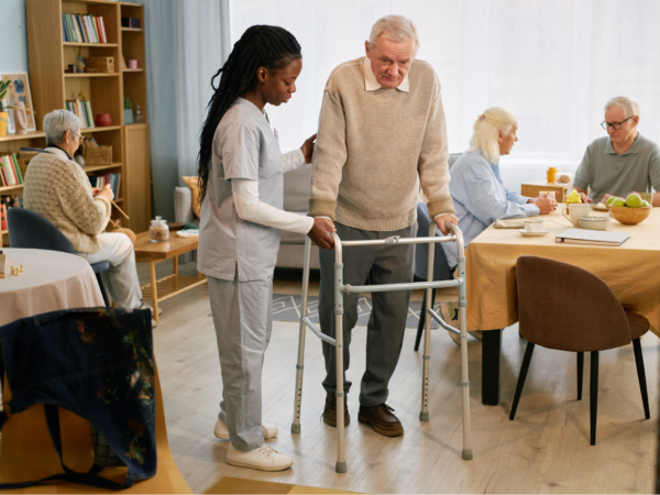 Home healthcare provider reviewing patient information on laptop with senior client in living room setting using secure managed IT services