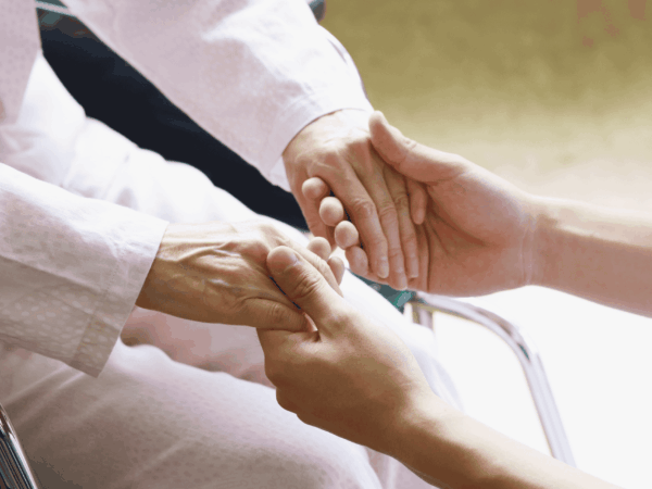 Caregiver holding elderly patient’s hands providing compassionate home-based care and secure, trust-focused healthcare support