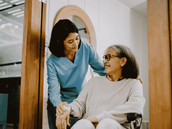 Caregiver assisting elderly woman in wheelchair at home highlighting the importance of secure systems to protect patient data in home-based care environments