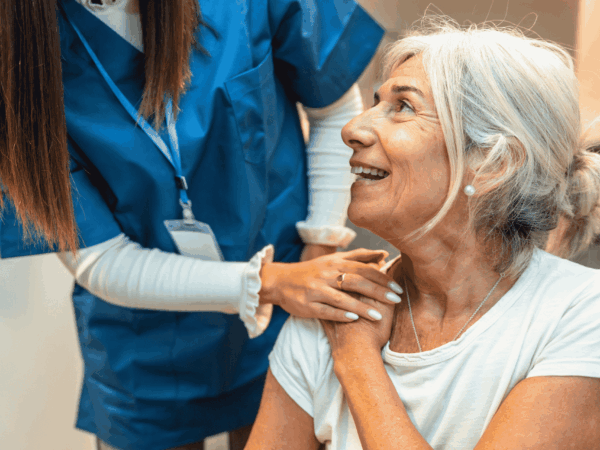 Caregiver supporting senior woman during home visit emphasizing the role of cybersecurity and data protection in delivering safe and reliable home-based care services