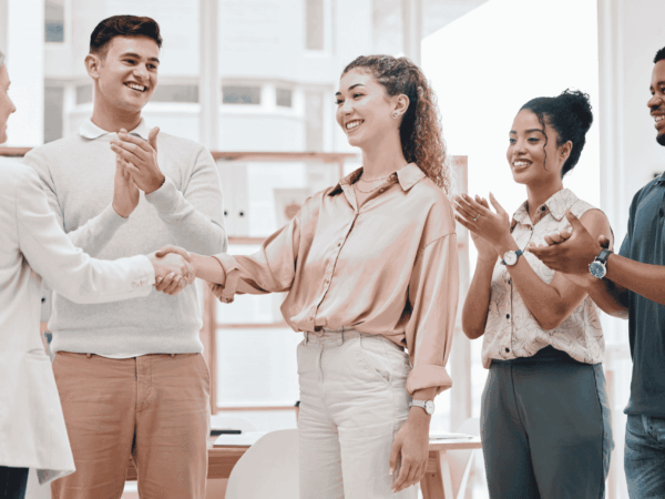 Business professionals shaking hands during a team meeting representing successful employee onboarding and workplace collaboration for home care agencies