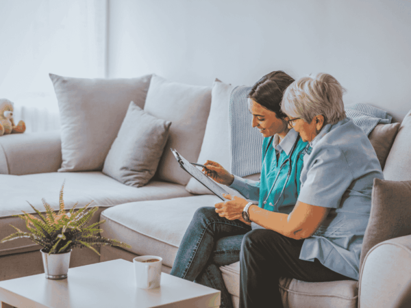 Home-based care professionals reviewing patient information together in a living room setting emphasizing reliable network connectivity and secure healthcare communication