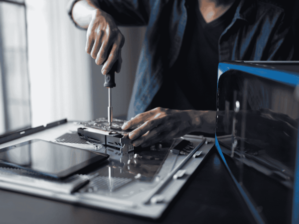 Technician performing computer hardware maintenance and device preparation, illustrating IT equipment deployment and lifecycle management for home-based care companies