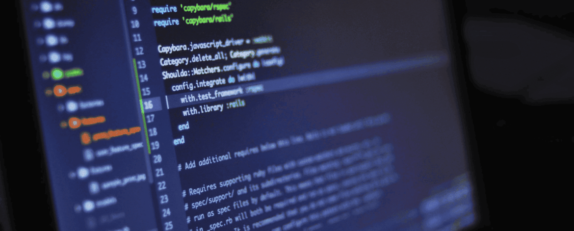 Close-up of a laptop screen showing a dark-themed code editor with Ruby on Rails test configuration and Copybara integration code, complete with line numbers, syntax-colored require statements, and comments.