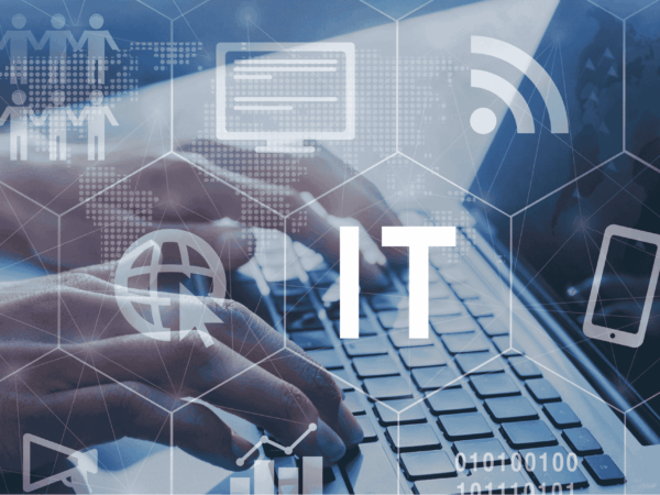 Close-up of hands typing on a laptop keyboard, overlaid with a semi-transparent hexagonal grid featuring a large “IT” label and icons for a globe with cursor, computer monitor, Wi-Fi, smartphone, user group, and data chart against a faint world-map background.