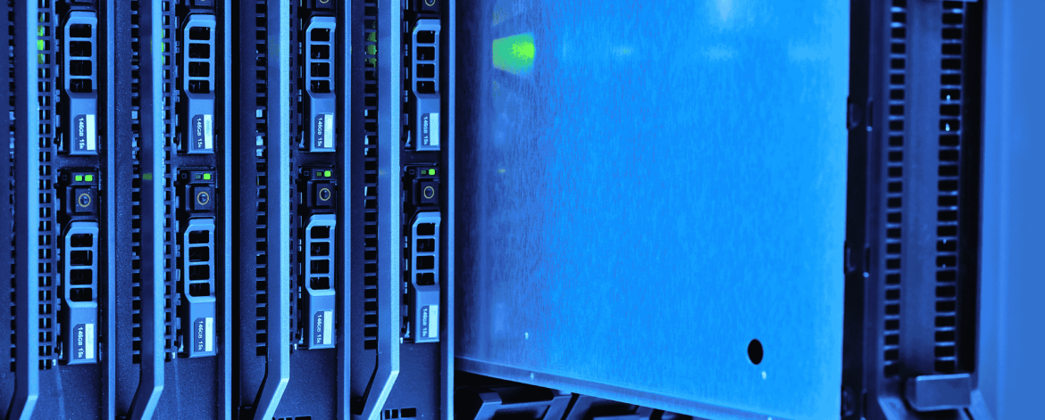 Close-up view of a data center server rack with multiple blade servers installed. One server blade is partially pulled out, revealing its metallic casing and internal green indicator lights. The image has a cool blue tone, emphasizing the high-tech environment.
