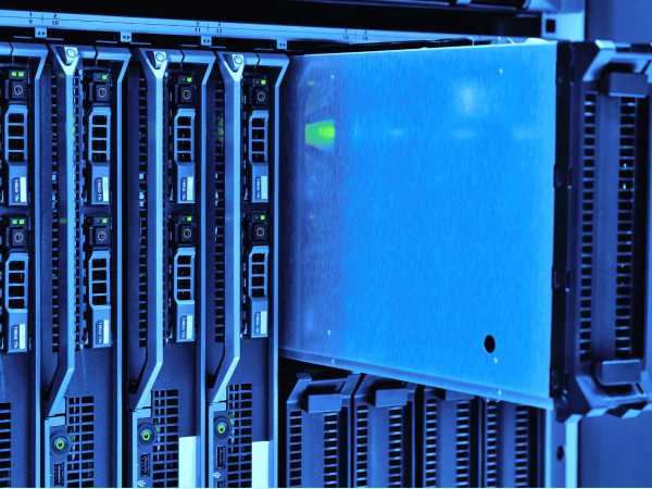 Close-up view of a data center server rack with multiple blade servers installed. One server blade is partially pulled out, revealing its metallic casing and internal green indicator lights. The image has a cool blue tone, emphasizing the high-tech environment.