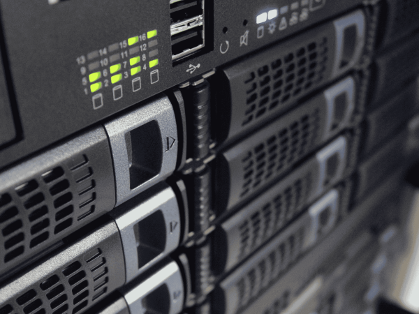 Close-up view of server racks with multiple hard drive bays and indicator lights, showing an active data center or IT infrastructure setup.