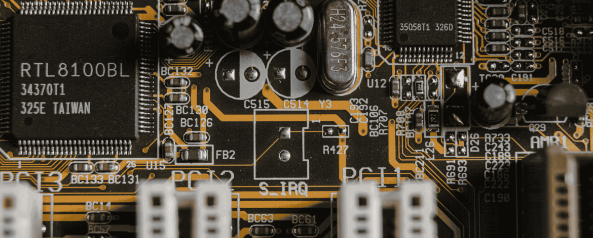 Close-up of a computer motherboard with integrated circuits, capacitors, and PCI slots, representing IT hardware and tech support services for businesses in the San Francisco Bay Area.