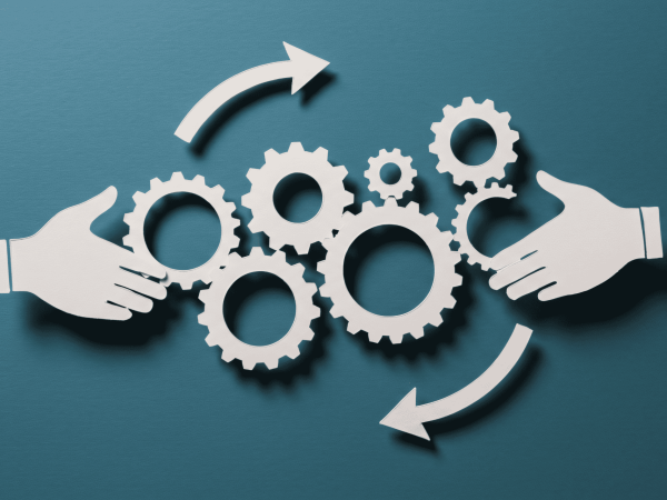 Hands exchanging interconnected gear icons symbolizing a coordinated IT hardware lifecycle management process with continuous improvement.