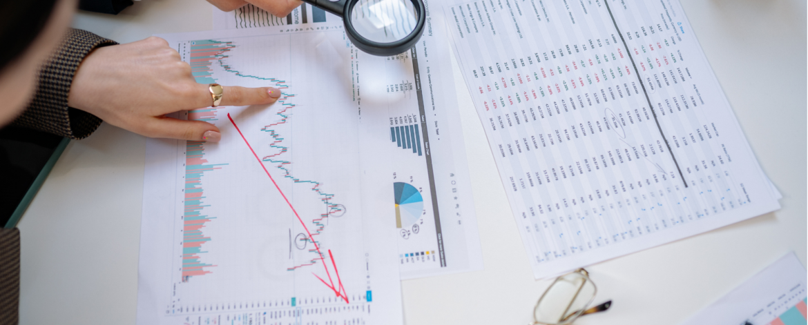 Business team analyzing financial and technology performance reports with magnifying glass to assess IT technical debt and cybersecurity risk