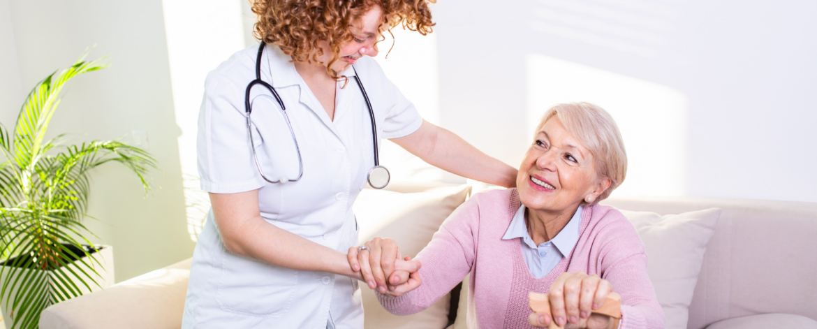 Home healthcare nurse assisting senior patient with mobility support during in home care visit supported by secure healthcare IT systems