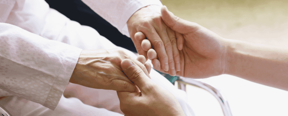 Caregiver holding elderly patient’s hands providing compassionate home-based care and secure, trust-focused healthcare support
