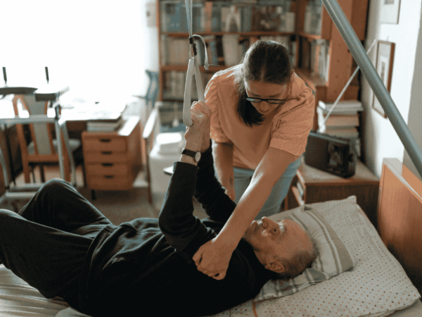 Caregiver assisting elderly patient with physical therapy at home highlighting need for secure and reliable endpoint protection in home-based care.