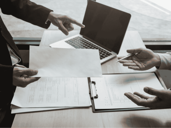 Manager conducting an employee offboarding discussion in an office setting with documents and laptop visible representing structured staff transition processes