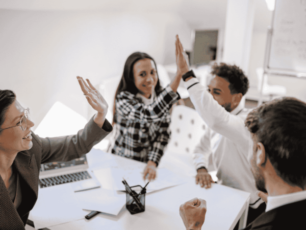 Team members celebrating together during a collaborative office meeting symbolizing engagement, communication, and employee onboarding success in home care organizations