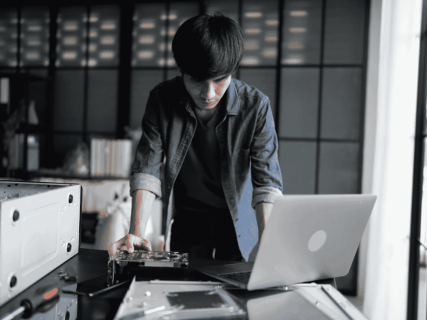 Hardware Lifecycle Management 3 IT technician servicing mobile devices and computer hardware at a workstation, supporting hardware lifecycle management, repairs, and device replacement planning for organizations
