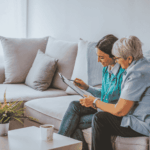 Home-based care professionals reviewing patient information together in a living room setting emphasizing reliable network connectivity and secure healthcare communication
