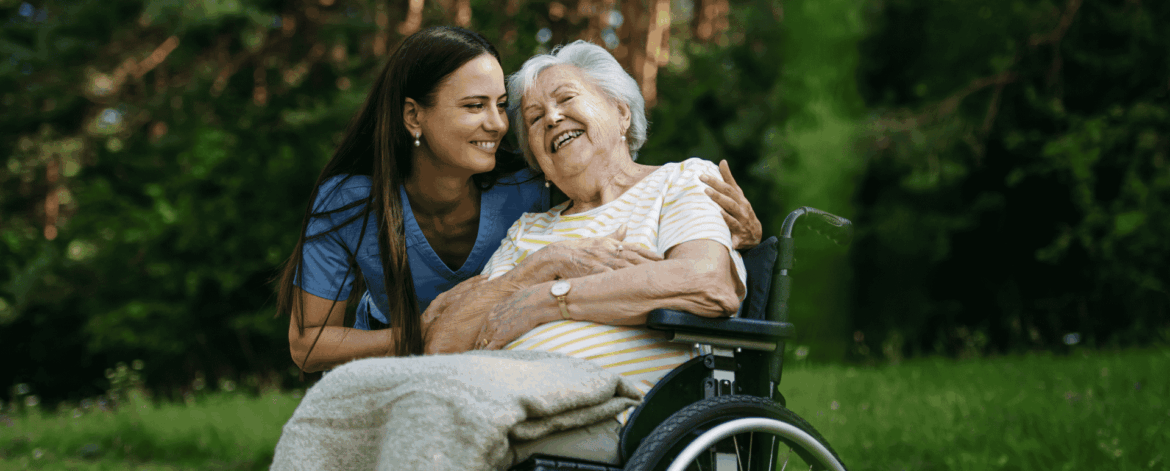 Caregiver supporting elderly woman in wheelchair outdoors highlighting the importance of reliable network infrastructure for continuous home-based care coordination.