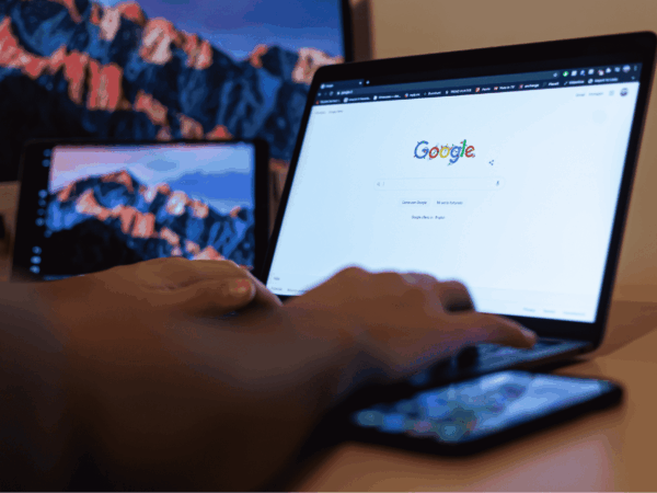 Google Workspace Best Practices for Home Based Care 2 Home care coordinator using Google Workspace on a laptop and smartphone to manage client records and team communication, with multiple devices displaying Google on screen.