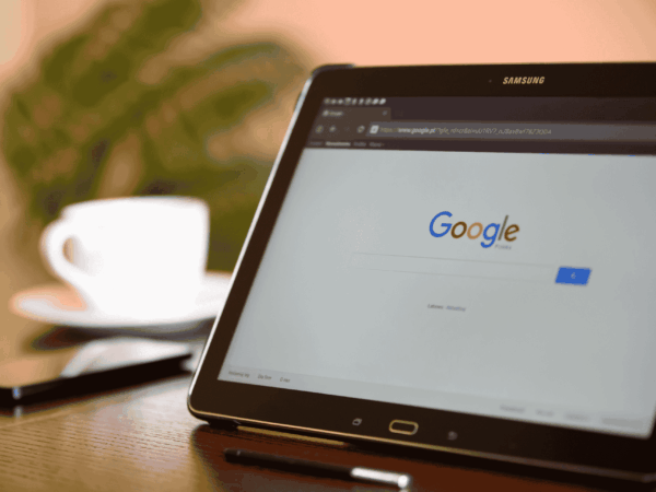 Google Workspace Best Practices for Home Based Care 3 Samsung tablet propped on a desk showing the Google homepage alongside a coffee cup, representing how home care administrators use Google Workspace to organize files, manage permissions, and maintain HIPAA compliance.