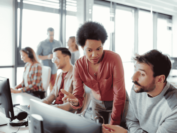 IT support team assisting employees with cybersecurity best practices and secure computer usage in an office environment