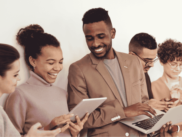 How Home Based Care Companies Can Manage and Secure their Teams Mobile Devices 1 Diverse team of home care professionals using smartphones, tablets, and laptops together, representing mobile device management and secure team communication for home-based care agencies.