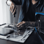 Technician performing computer hardware maintenance and device preparation, illustrating IT equipment deployment and lifecycle management for home-based care companies
