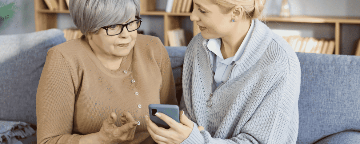 Home health clinician and an older adult reviewing a smartphone at home, the patient data a HIPAA business associate agreement for home health agencies protects.