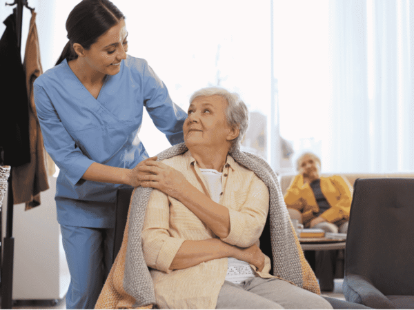 Caregiver holding an elderly client's hand during a home visit, the setting behind the HIPAA Security Rule update home health agencies are tracking in 2026.