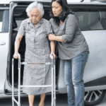 Caregiver steadying an older woman with a walker beside a van after a home visit, the care that precedes questions about HIPAA rules for deceased hospice patients.