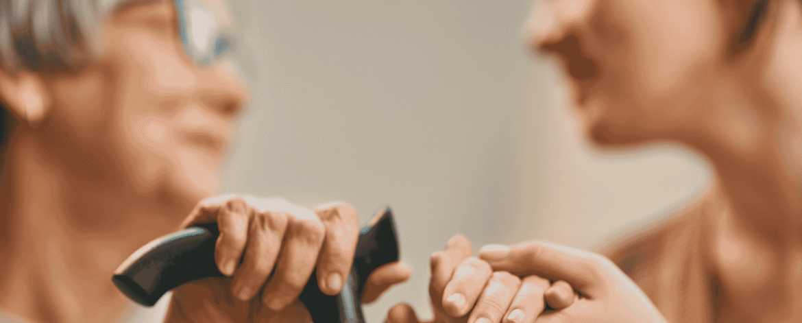 Caregiver holding an older adult's hand beside a walking cane during a home visit, the patient relationship behind HIPAA breach notification for home health agencies.