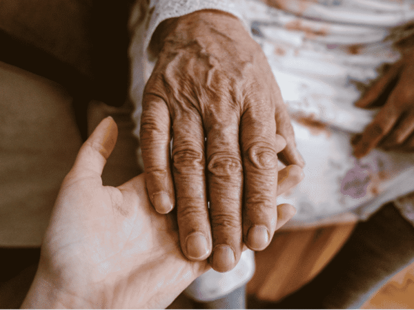 Nurse in blue scrubs settling a blanket around a seated senior client at home, the daily work behind the proposed HIPAA Security Rule for home health agencies.