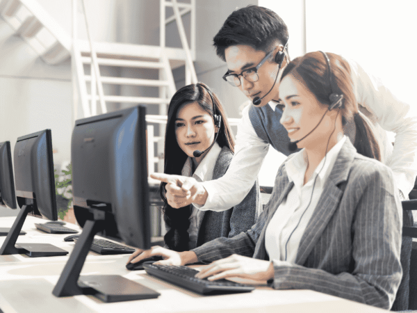 Support team in headsets working through a screen together at a shared desk, the vendor coordination a HIPAA shared responsibility matrix puts in writing.