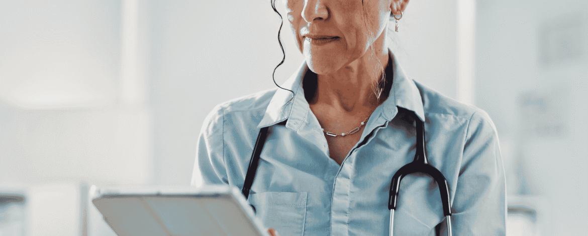 Clinician with a stethoscope reading patient records on a tablet, the access that decides whether home health agencies need a BAA with a staffing agency.