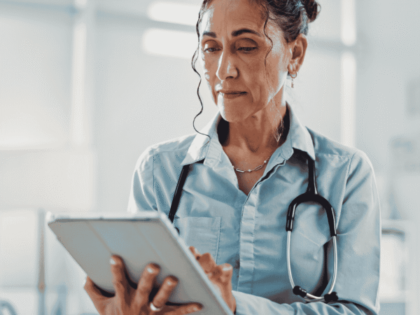 Image 3_9.11.26 Clinician with a stethoscope reading patient records on a tablet, the access that decides whether home health agencies need a BAA with a staffing agency.