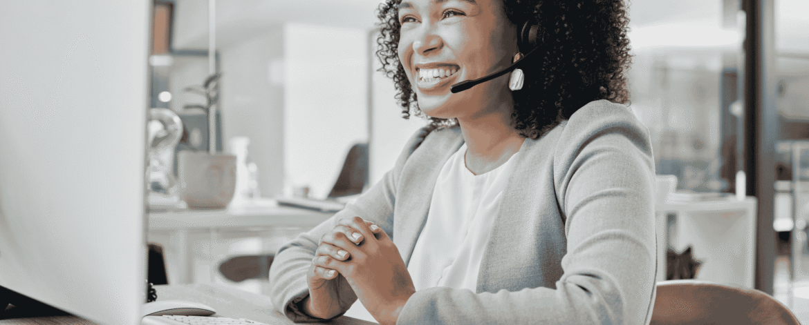 Smiling specialist wearing a headset at an office workstation, fielding questions like whether you can outsource the HIPAA security officer role to an IT provider.