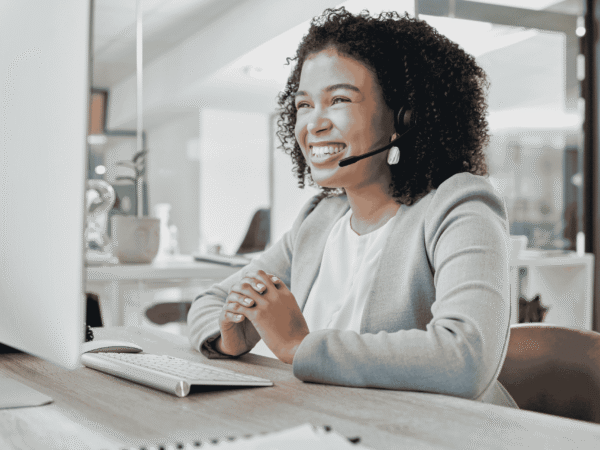 Smiling specialist wearing a headset at an office workstation, fielding questions like whether you can outsource the HIPAA security officer role to an IT provider.